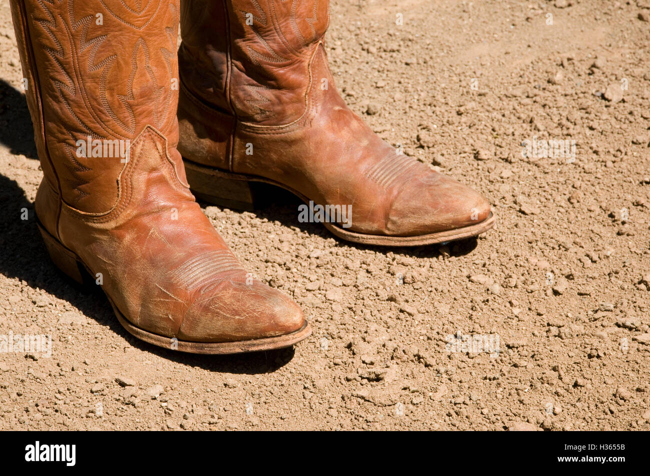 Two dirty western cowboy boots standing on dry dirt Stock Photo