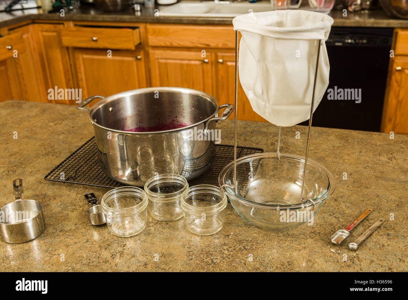 Items needed to make homemade jelly or jam at home.  Strainer, bowl, measuring cups, and kettle Stock Photo
