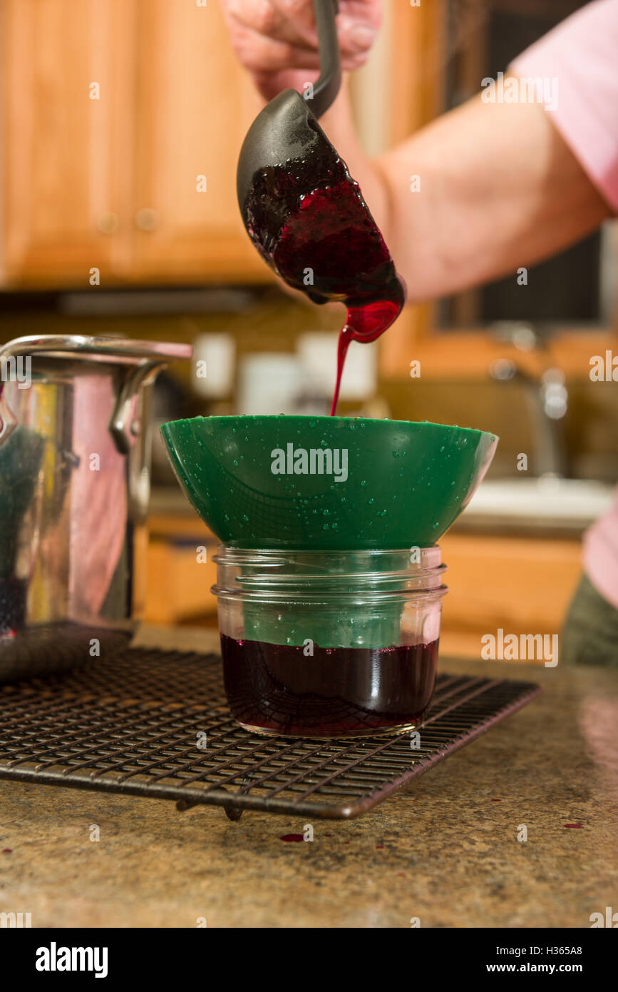 Pouring the grape juice in canning jars to make homemade jelly or jam. Stock Photo