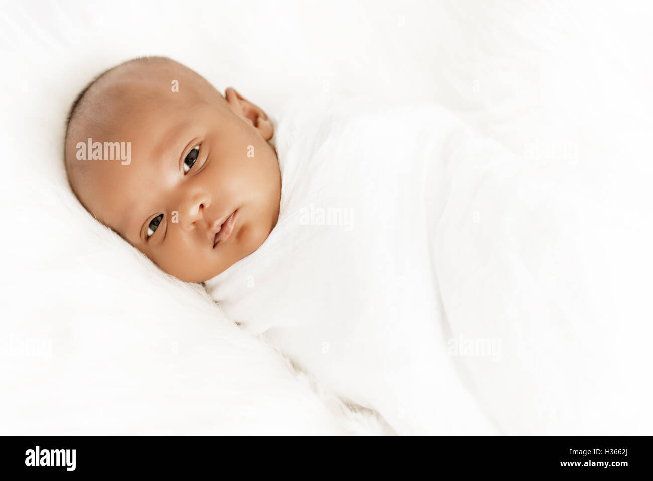 Three weeks old baby sleeping on white blanket cute infant newborn lying down close up shot eyes open Stock Photo