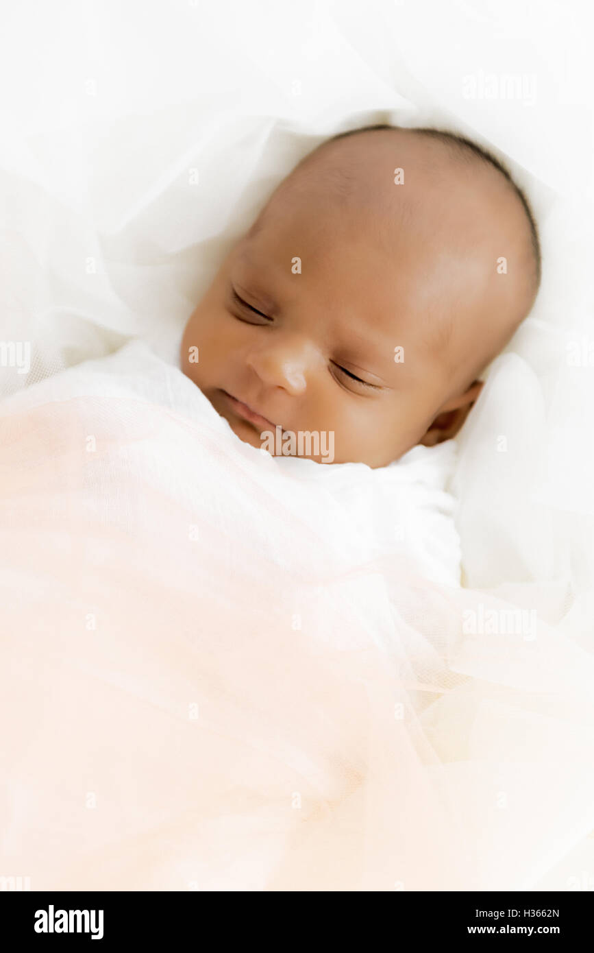 Three weeks old baby sleeping on white blanket cute infant newborn lying down close up shot eyes closed Stock Photo