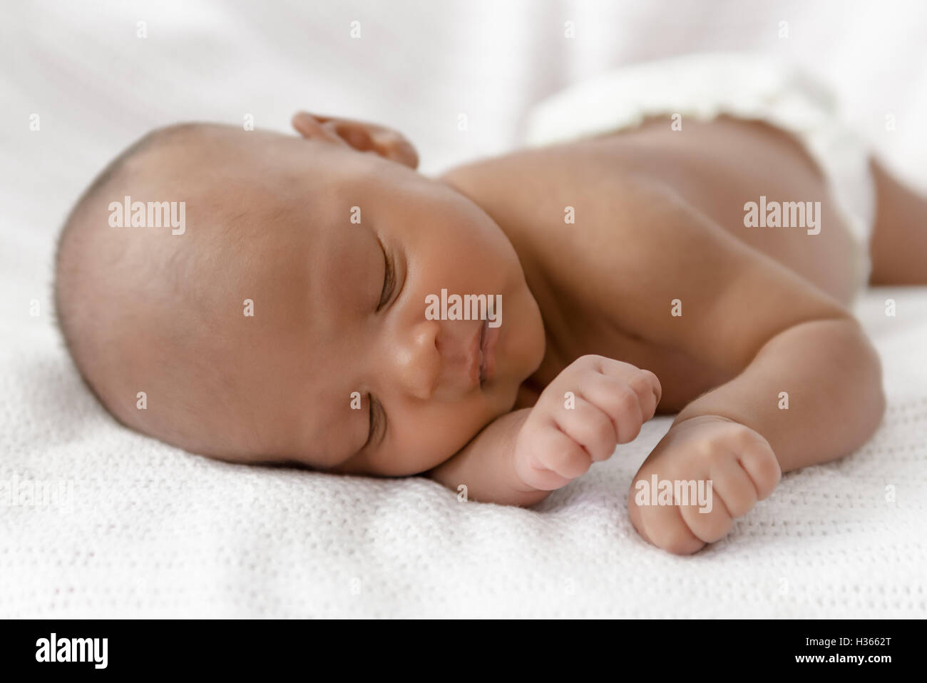 Three weeks old baby sleeping on white blanket cute infant newborn lying down close up shot eyes closed Stock Photo