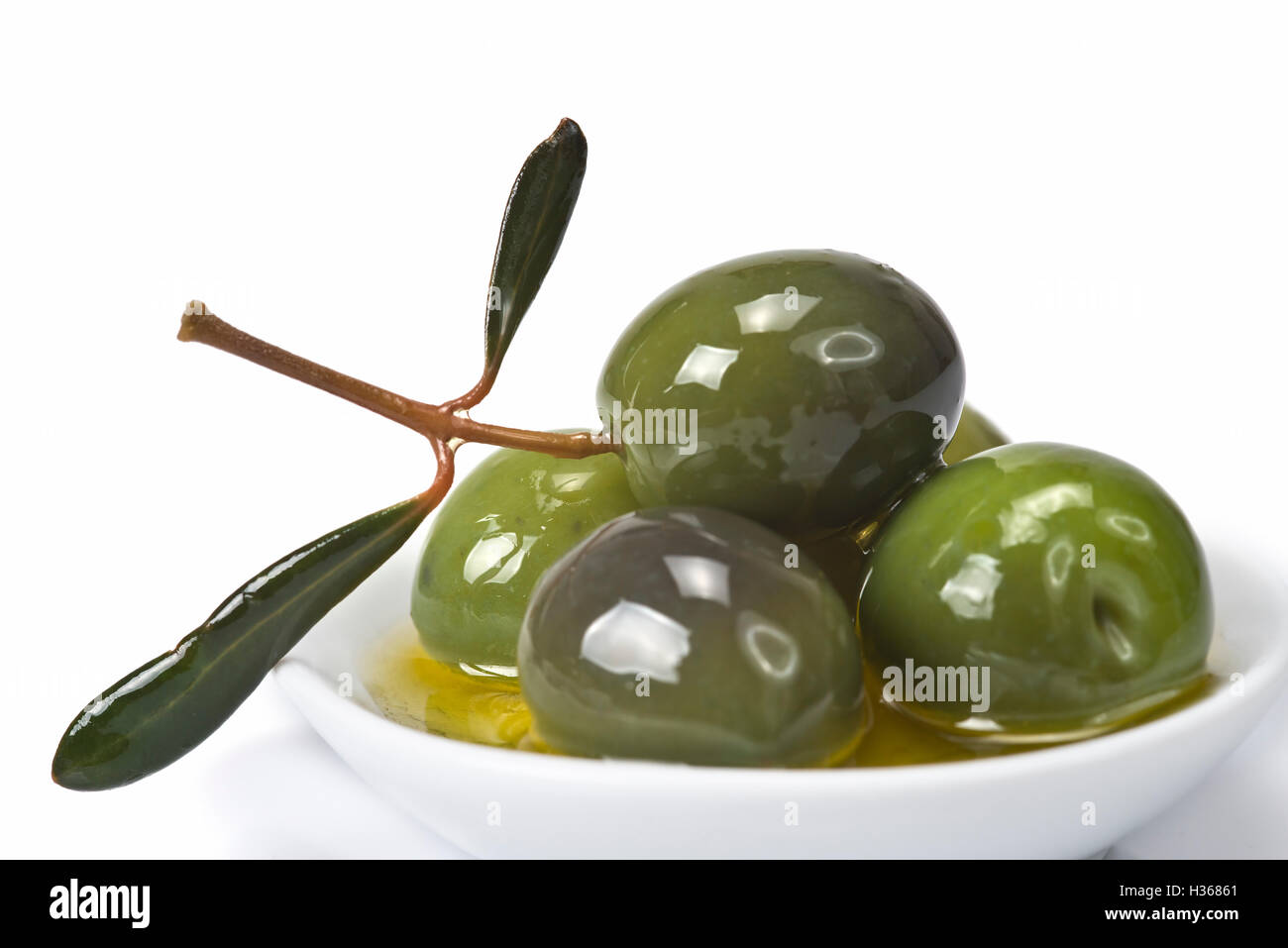 Green olives in a china spoon over a white background Stock Photo Alamy