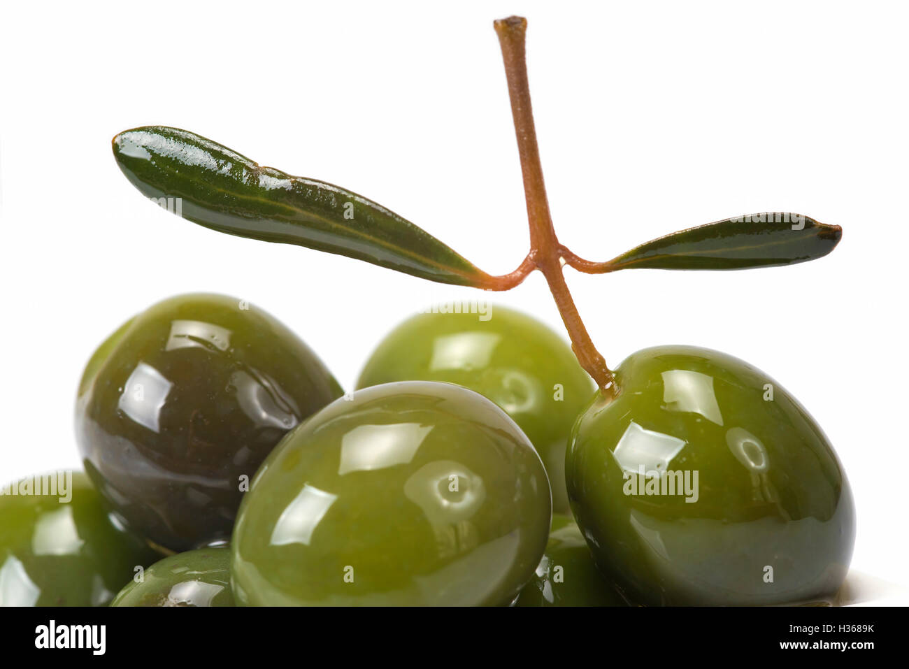 Green olives in a china spoon over a white background Stock Photo Alamy