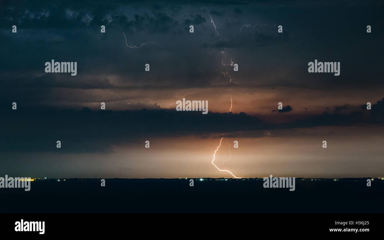 Massive cloud to ground lightning bolts hitting the horizon of city