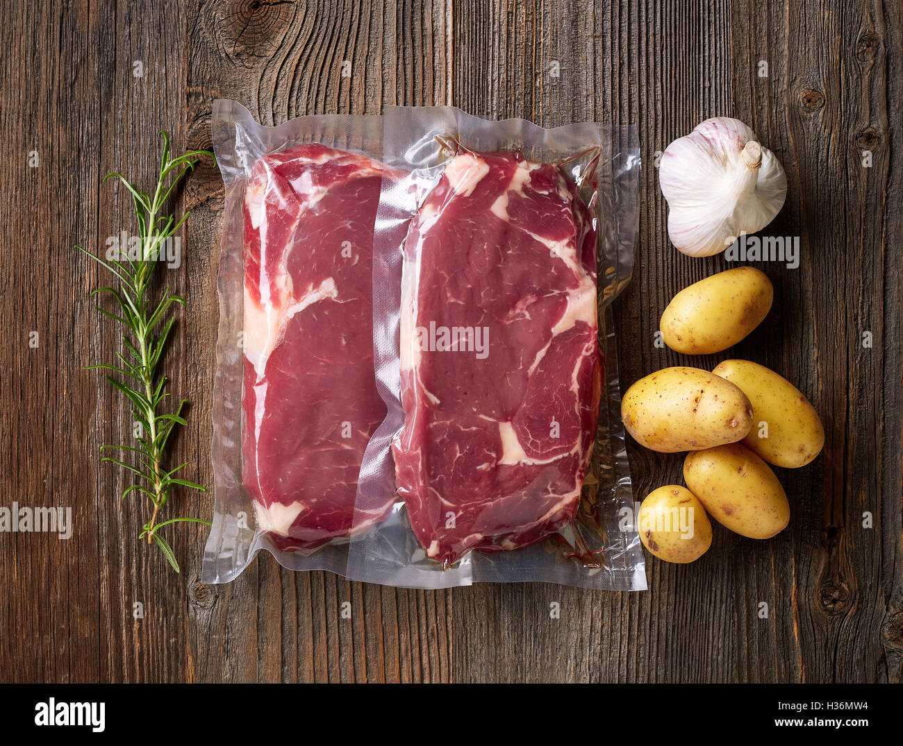 Fresh beef steak for sous vide cooking on wooden table Stock Photo - Alamy
