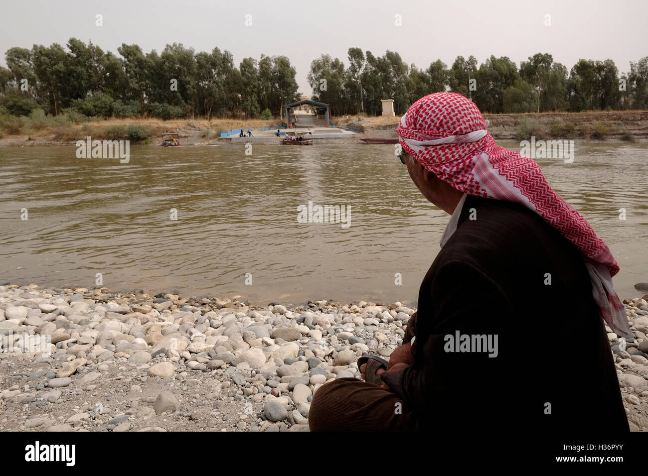A Kurdish man on the Syrian side of Tigris river gazing at the Faysh Khabur or Fishkhabur - Semalka border crossing from Iraq’s Kurdistan region into Syria’s northeastern Kurdish area Stock Photo