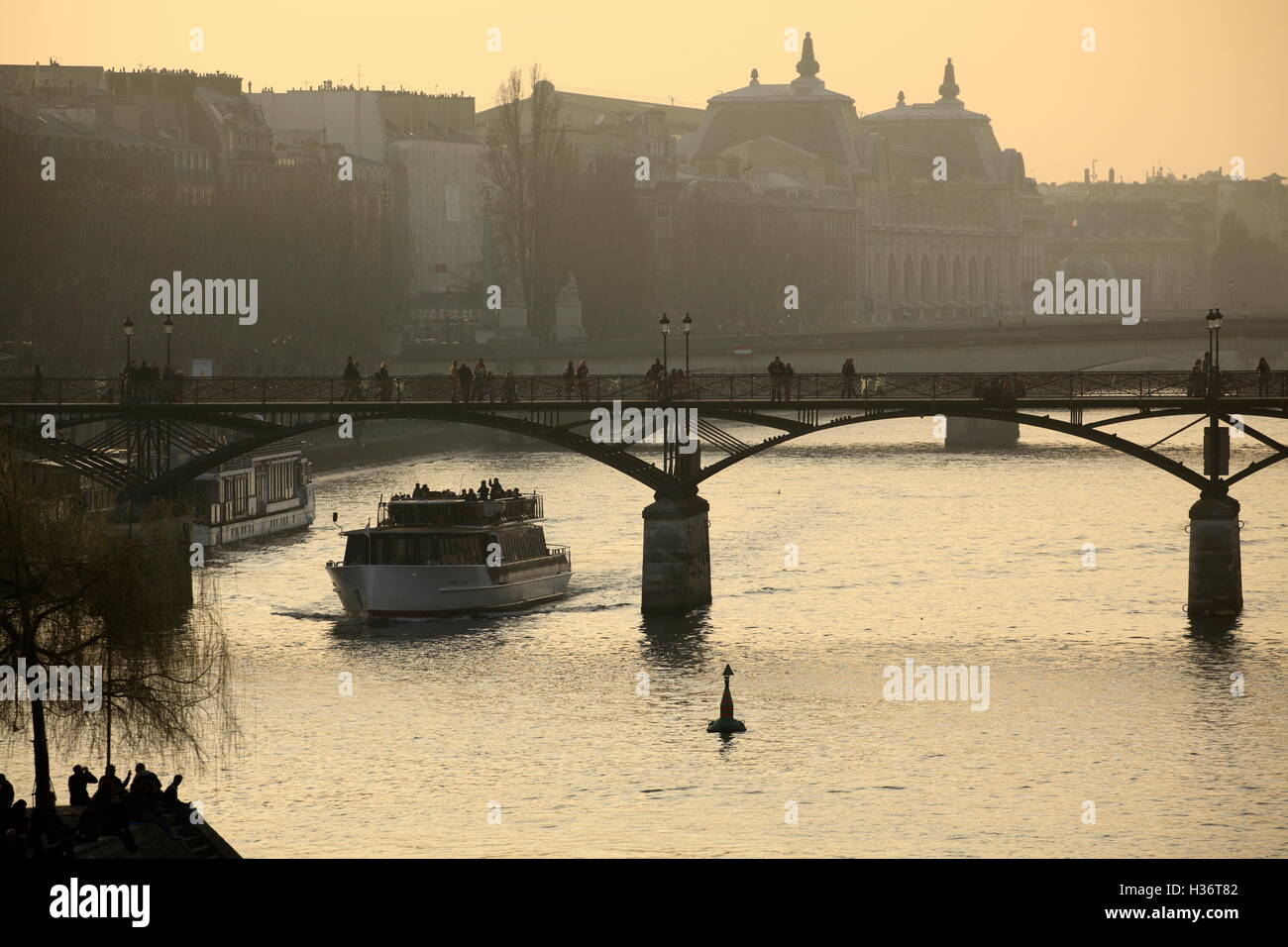 A tour boat under Passerelle des Arts aka Pont des Arts (Bridge of the Arts) over River Seine during sunset. Paris. France Stock Photo
