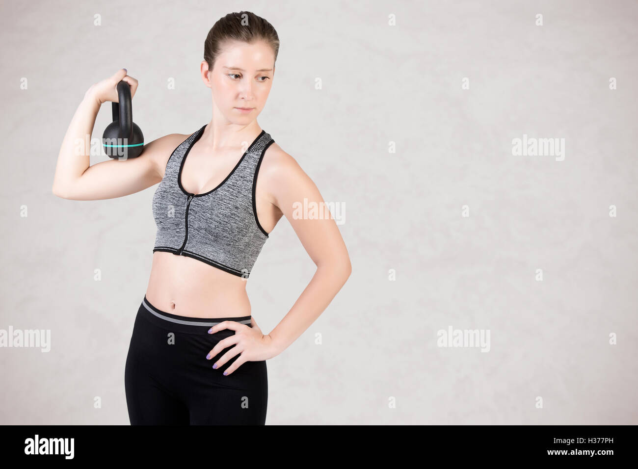 Fit woman working out with a kettlebel and similingl, isolated in grey Stock Photo