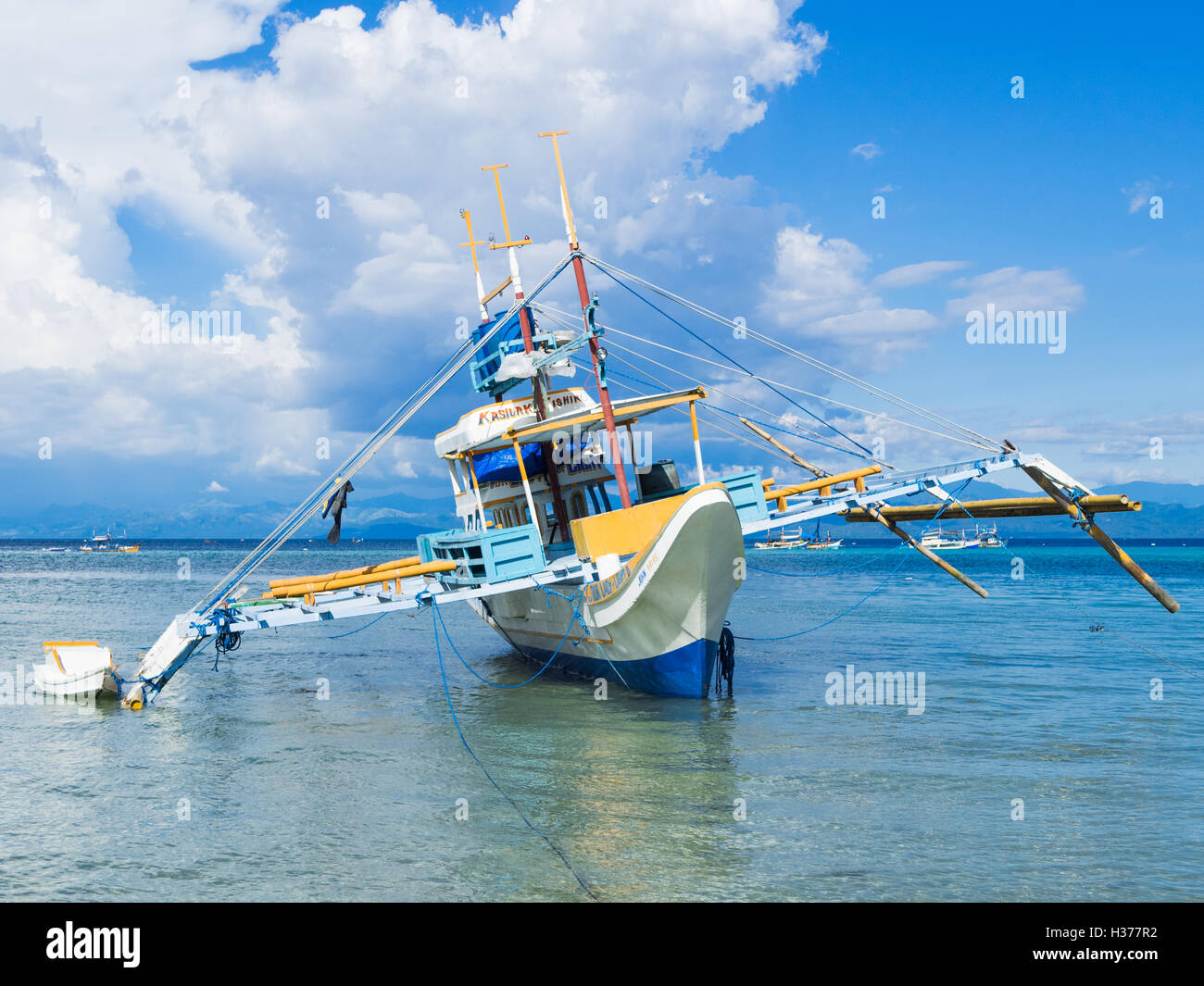 Fishing vessel with outriggers at low tide by the village of