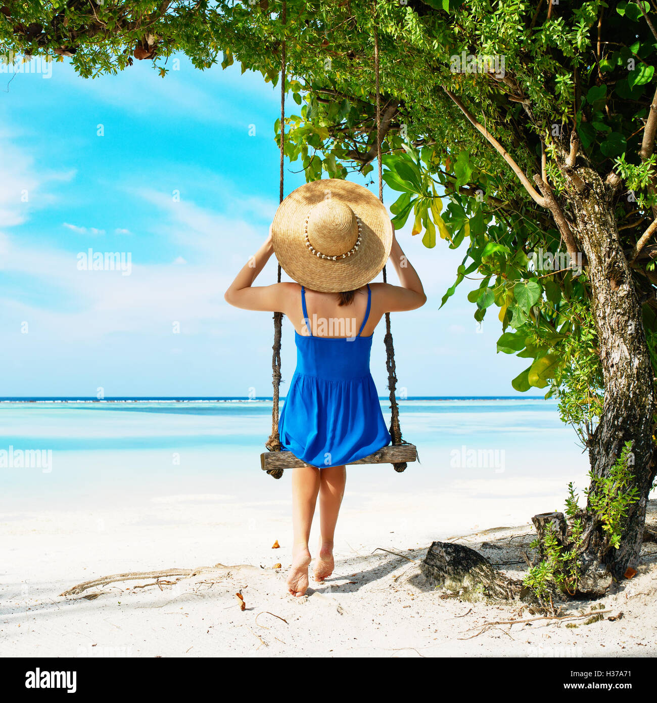 Woman in blue dress swinging at beach Stock Photo - Alamy