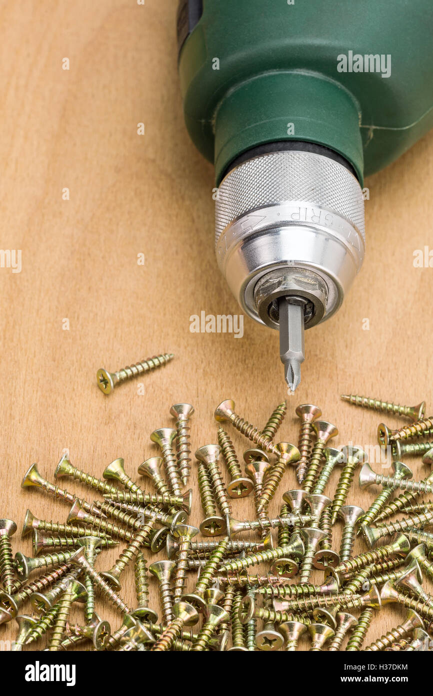 Electric drill with screws on wooden background Stock Photo Alamy