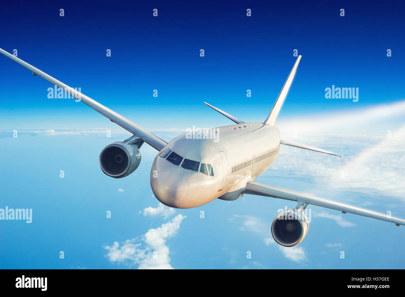 Commercial jet plane flying above clouds in day light Stock Photo