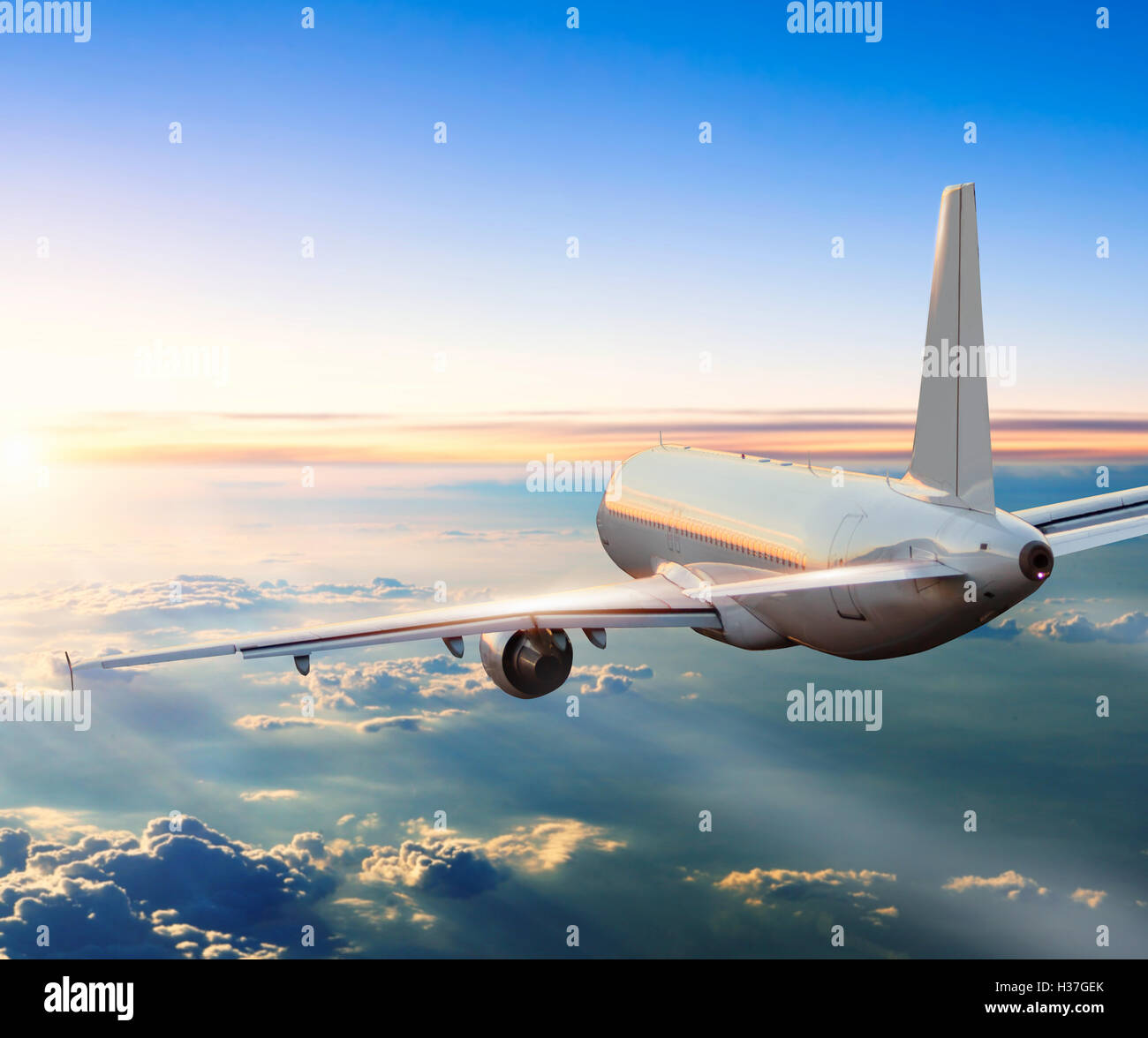 Commercial airplane flying above clouds in dramatic sunset light Stock ...