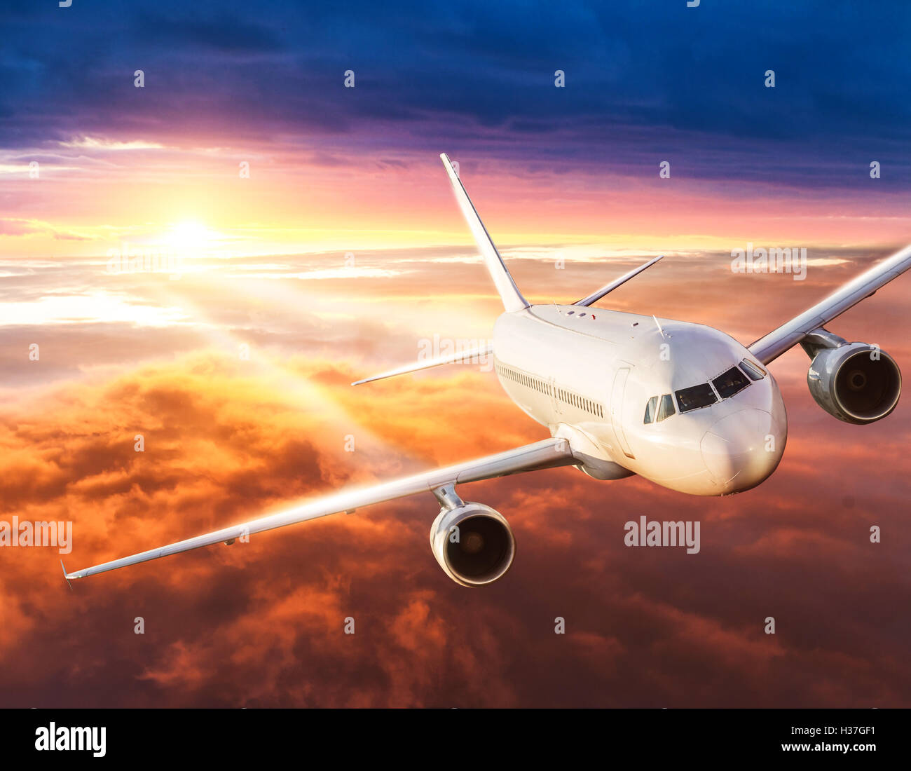 Commercial airplane flying above clouds in dramatic sunset light Stock ...