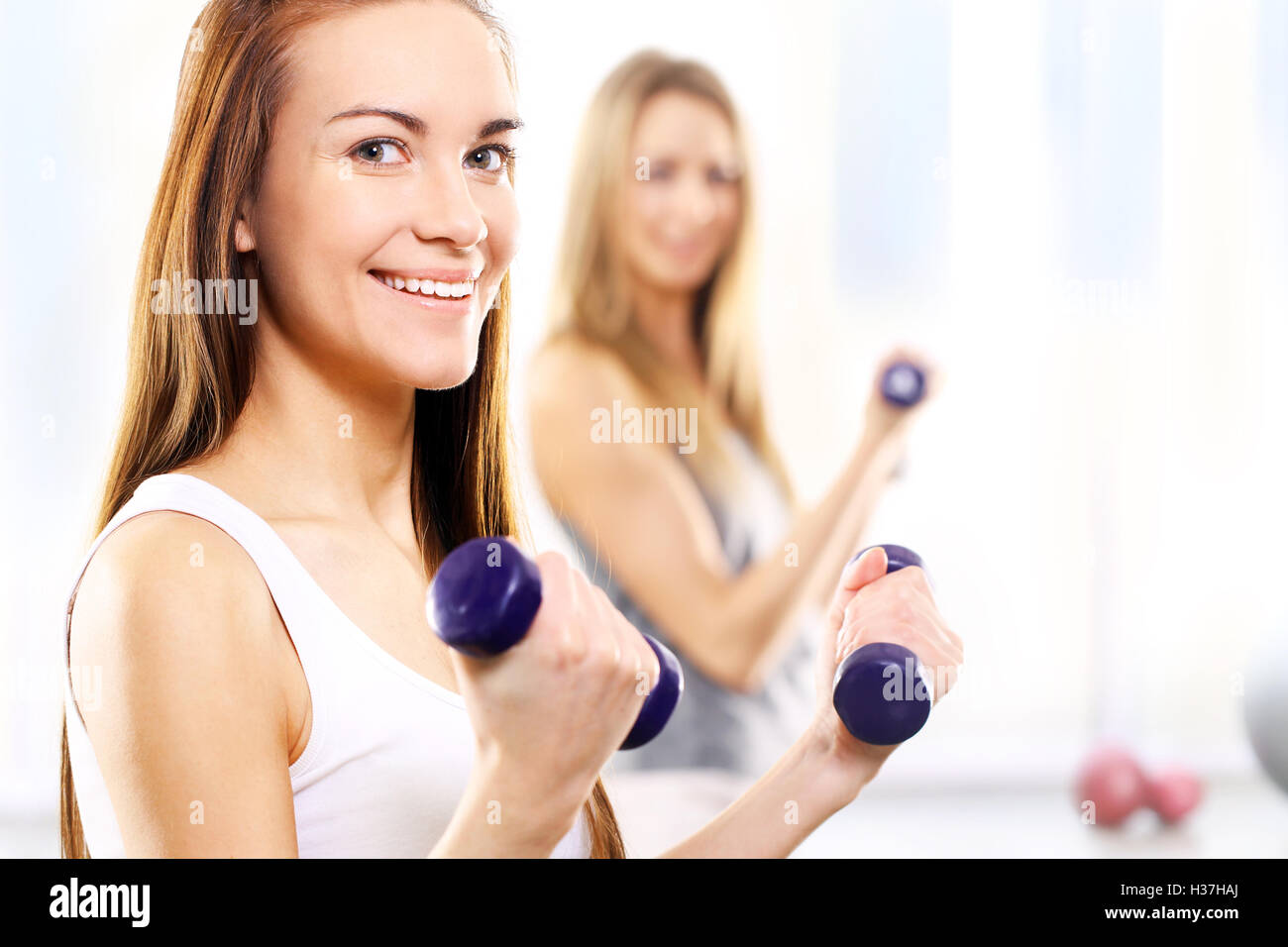 Training with weights, two young women in the gym Stock Photo