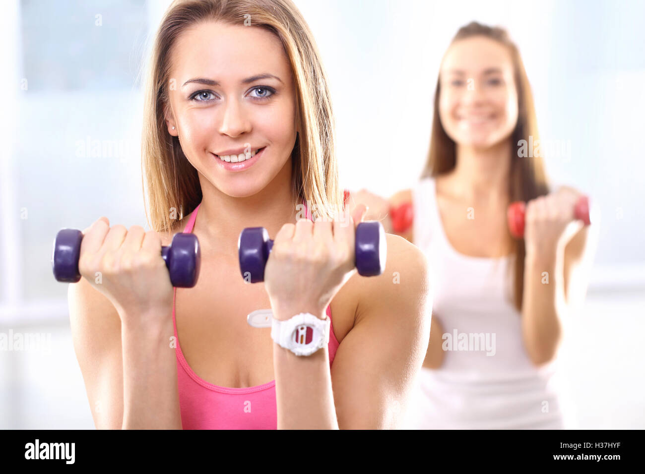 Training with weights, two young women in the gym Stock Photo