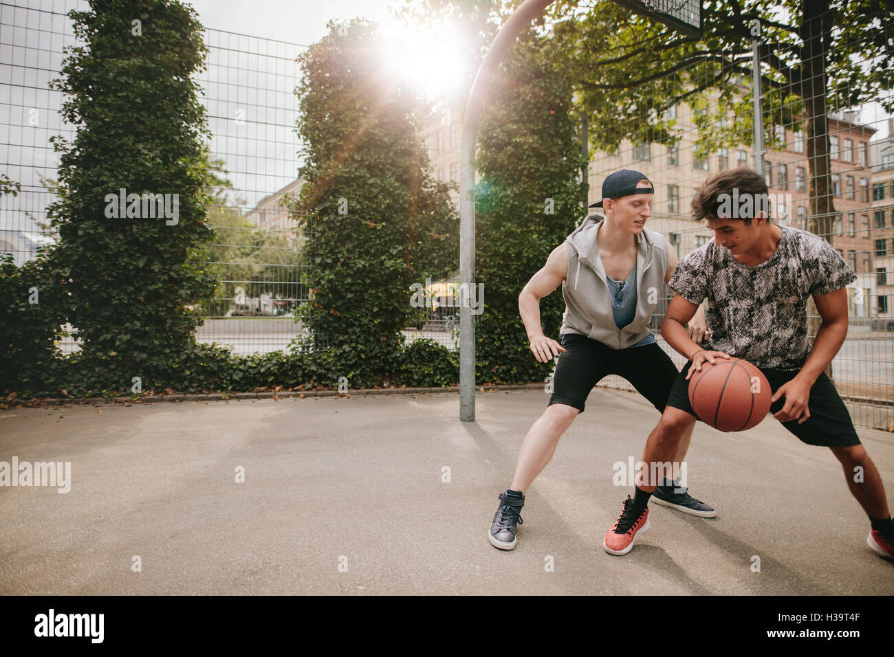 Young men playing a game of basketball on an outdoor court. Teenage friends playing basketball against each other. Stock Photo
