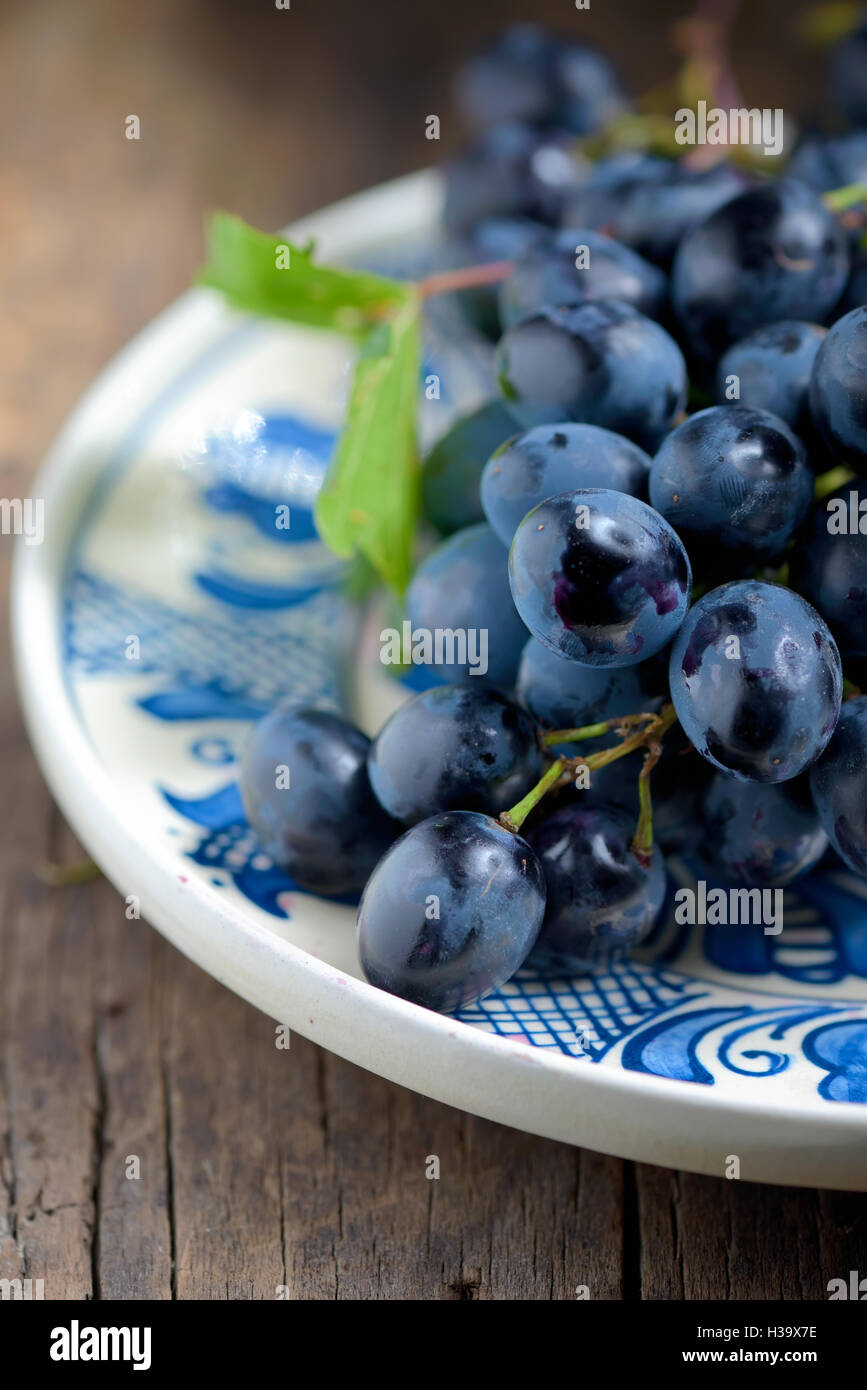 black grapes on plate on wooden table Stock Photo