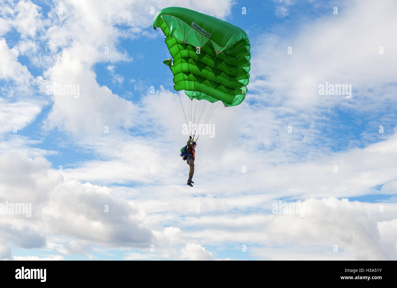 Single parachute jumper on a wing parachute on blue sky background