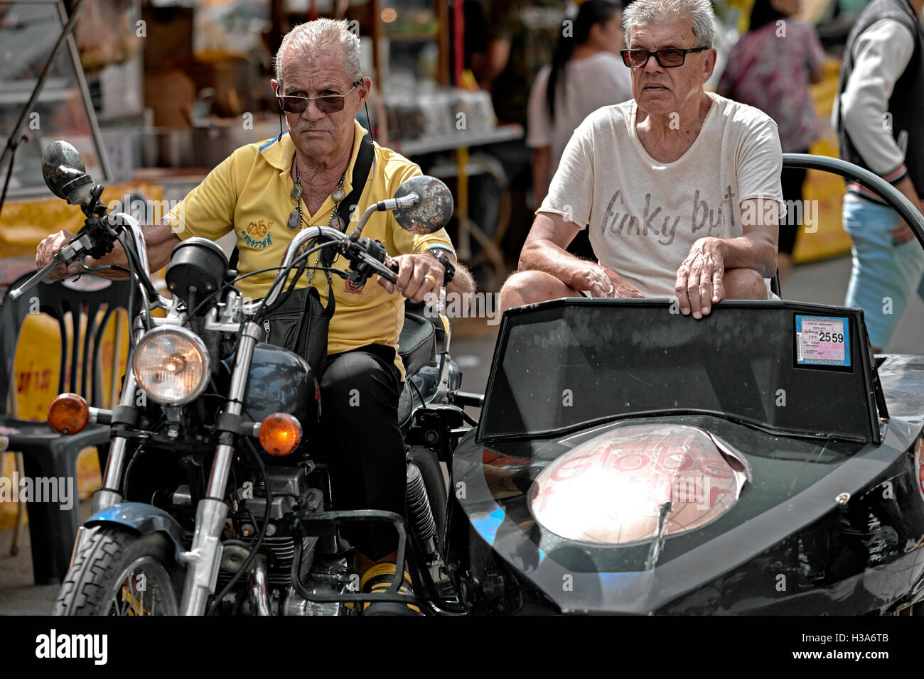Motorcycle sidecar. Senior Caucasian males riding a motorcycle and sidecar through a busy market