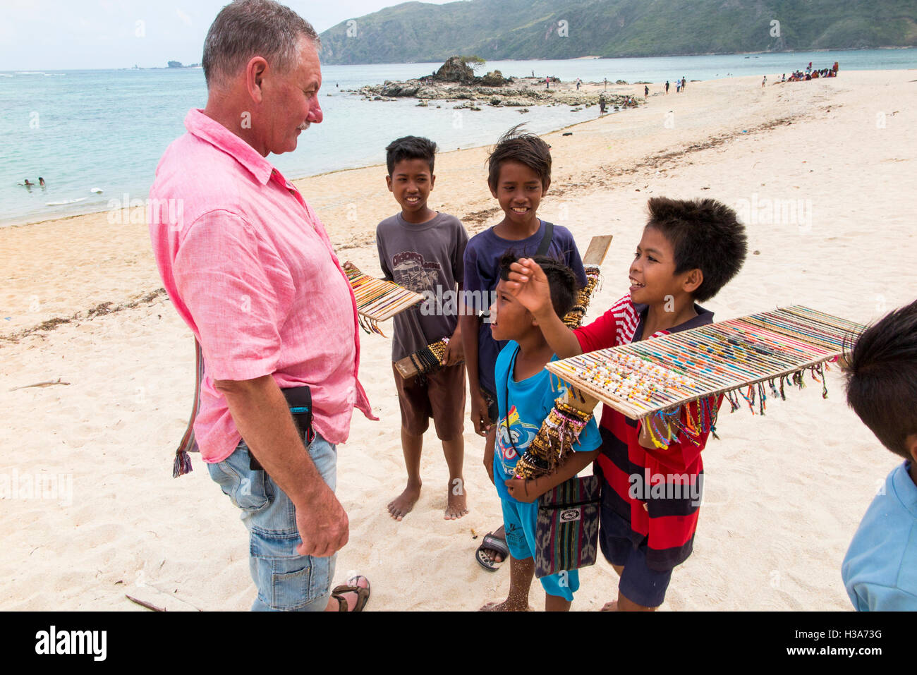 Indonesia, Lombok, Selong Blanak, tourism, child hawkers hassling tourist to buy bracelets on beach Stock Photo