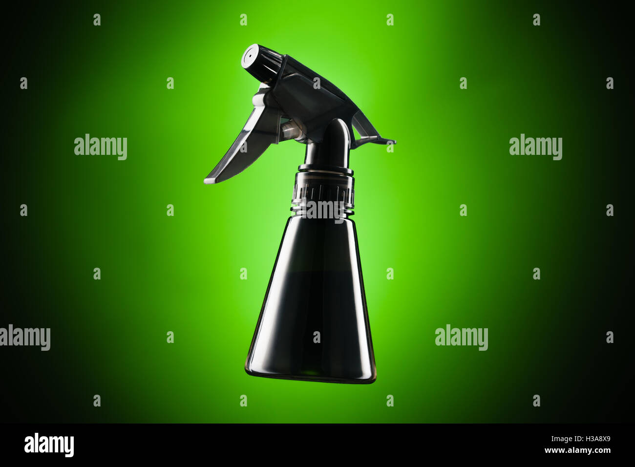 Black mini spray bottle over green background Stock Photo