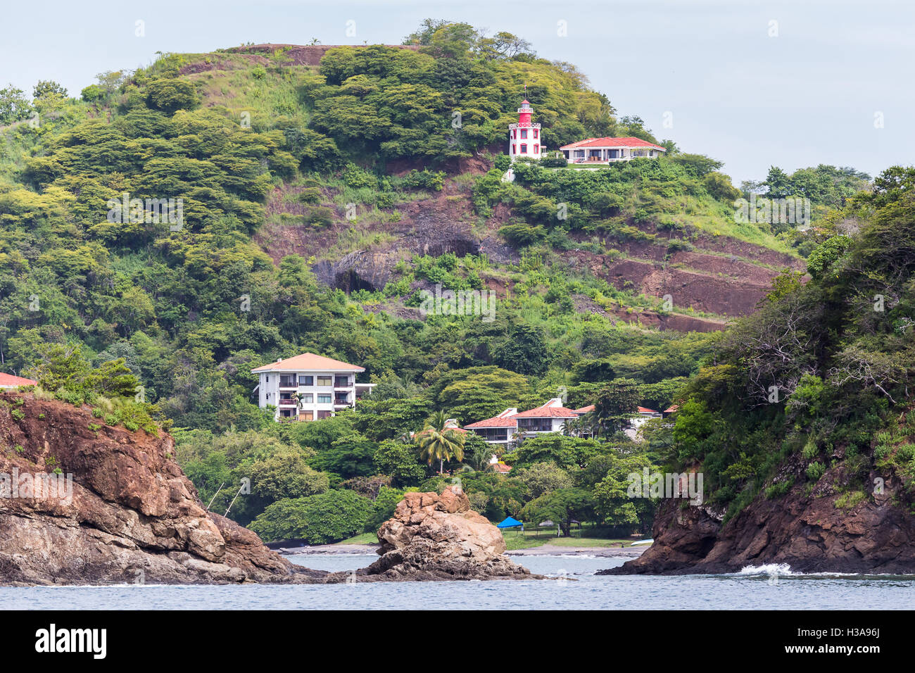 Houses occupy the slopes of Guanacaste as waves crash against the rocky coast. Stock Photo