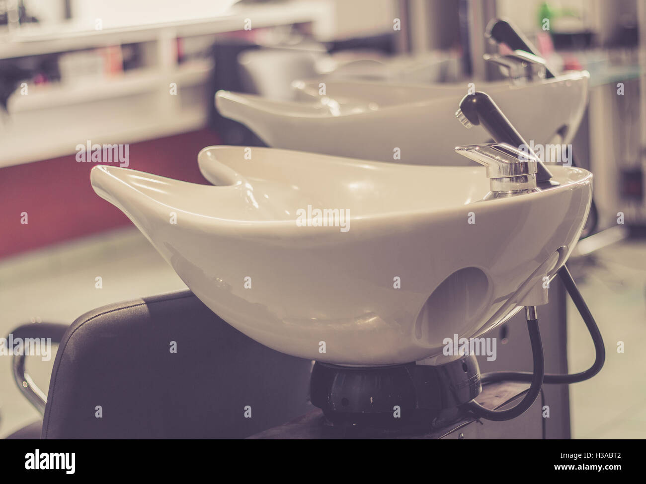 Beauty salon interior - a row of hair washing sinks - white washbasins for hairdresser Stock Photo