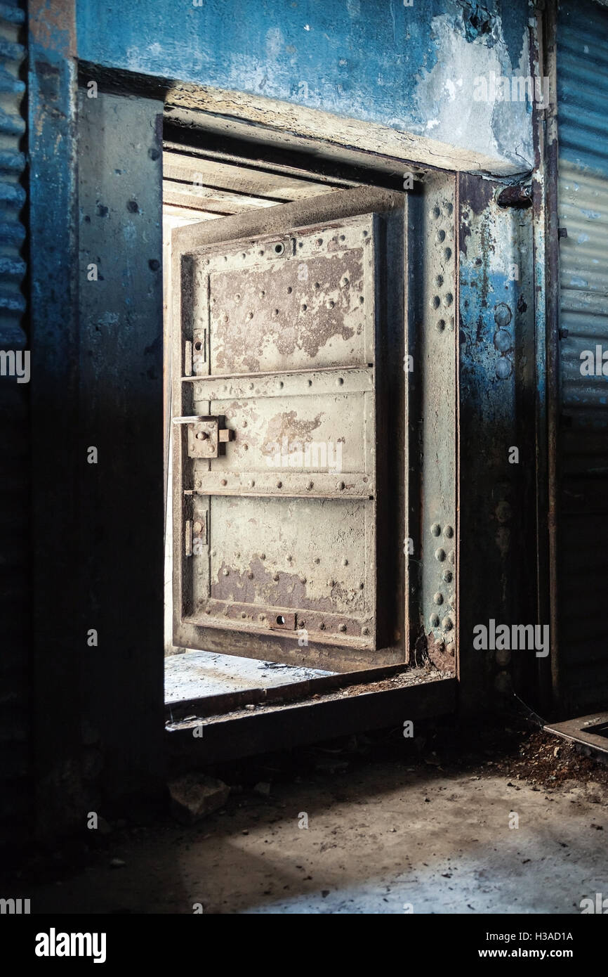 Abstract dark grungy industrial interior with blue rusted metal wall and open heavy steel door Stock Photo