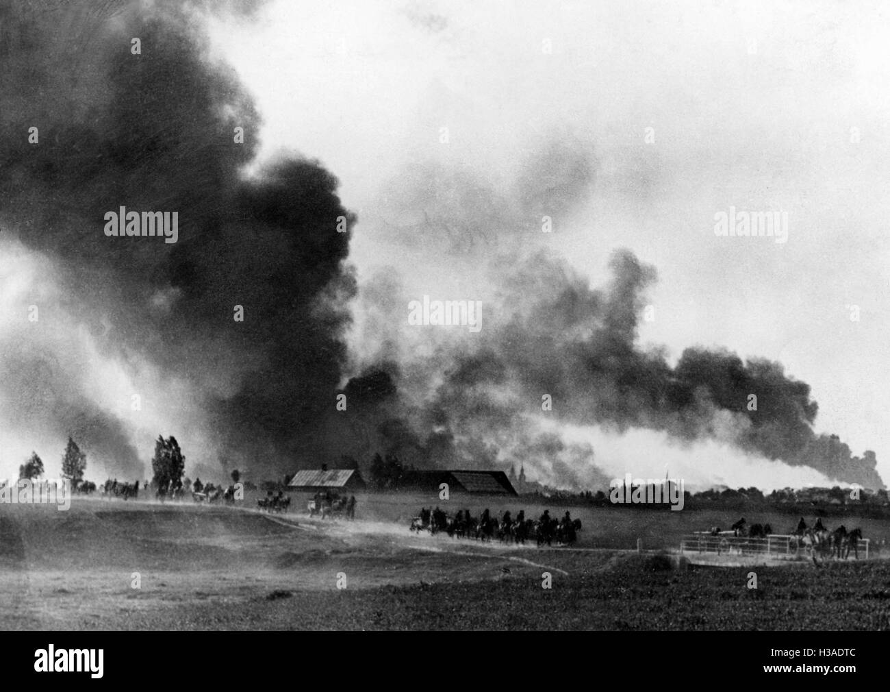 Column of the Wehrmacht passing by a burning village on the Eastern Front, 1941 Stock Photo