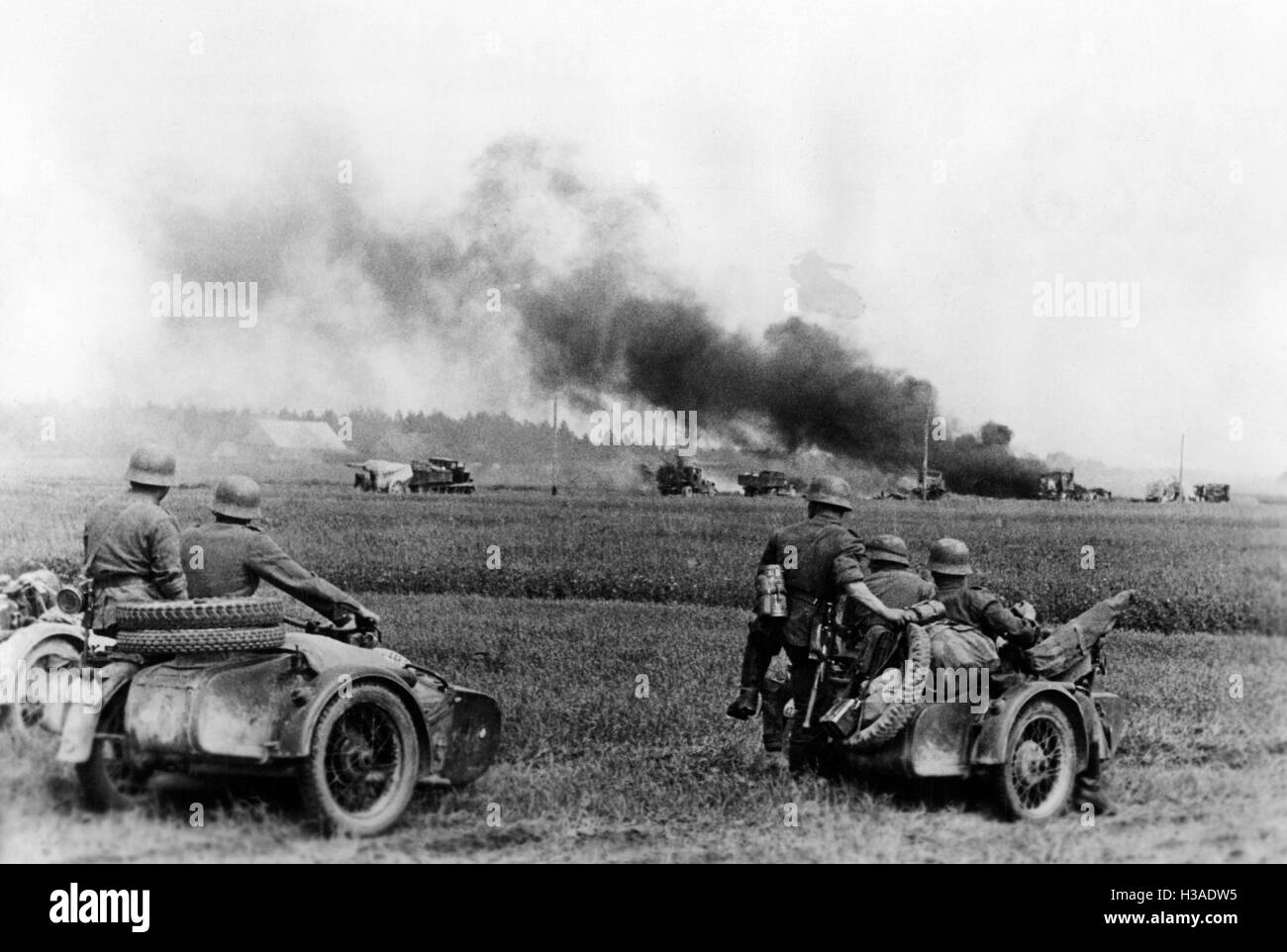 German motorcycle troops pass by burning Soviet vehicles, 1941 Stock Photo