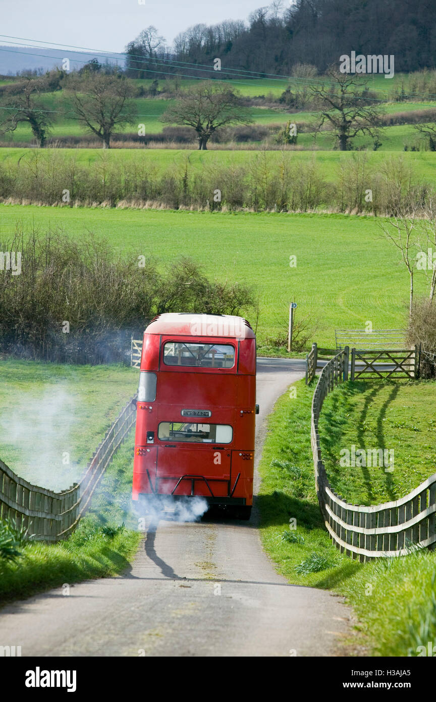 An old double decker red London bus driving through the Biritish ...