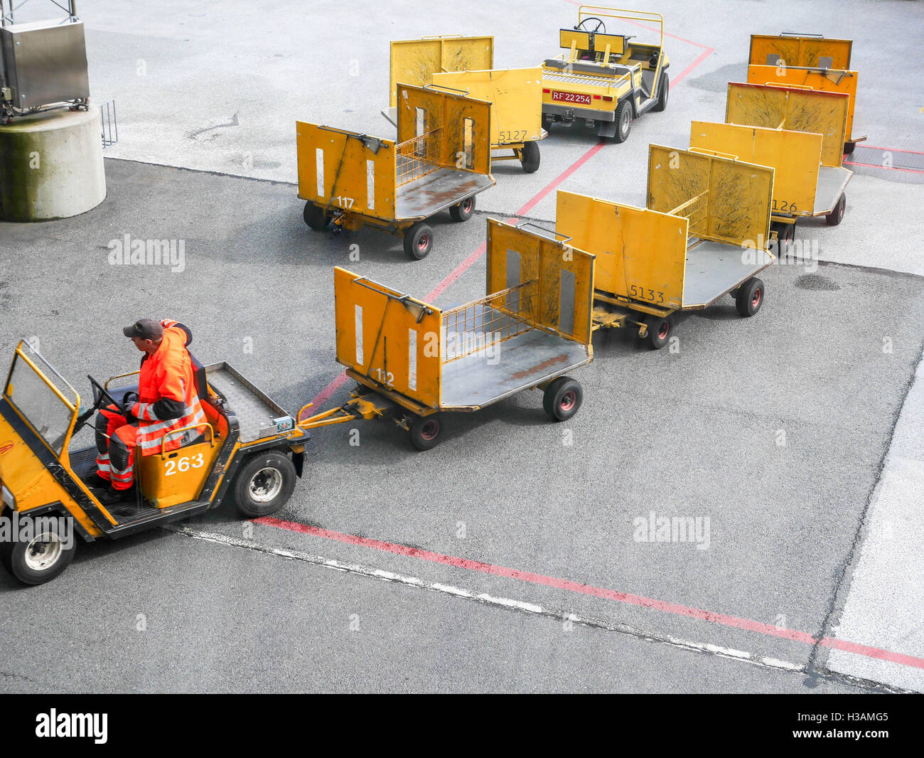 Airport workers are loading and unloading plane and using their small trains to carry heavy