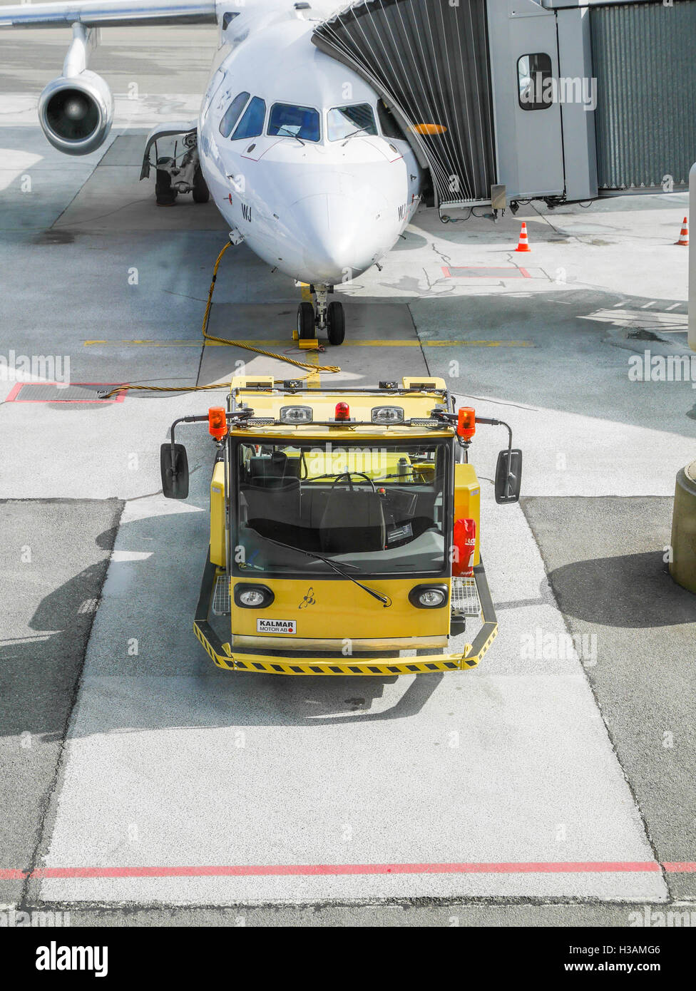 Airport workers are loading and unloading plane and using their small trains to carry heavy