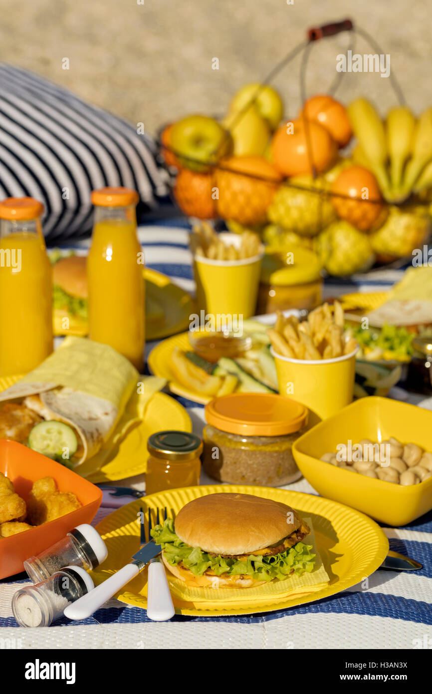 Summertime. A picnic on the beach. Burgers and pitas, vegetables and fruits. Selective focus. Stock Photo