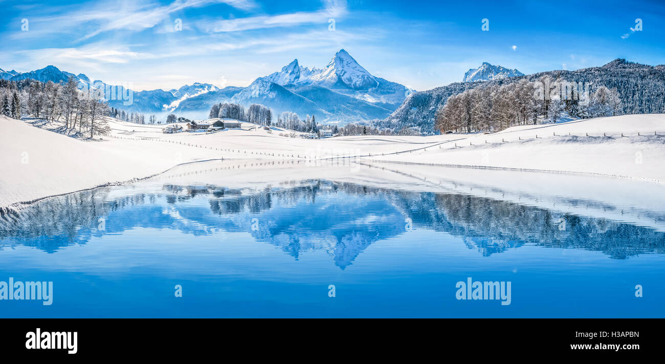 Beautiful white winter wonderland scenery in the Alps with snowy mountain summits reflecting in crystal clear mountain lake Stock Photo