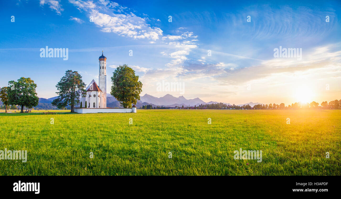 Panoramic view of famous St. Coloman church near Fussen in golden evening light at sunset in summer, Schwangau, Bavaria, Germany Stock Photo