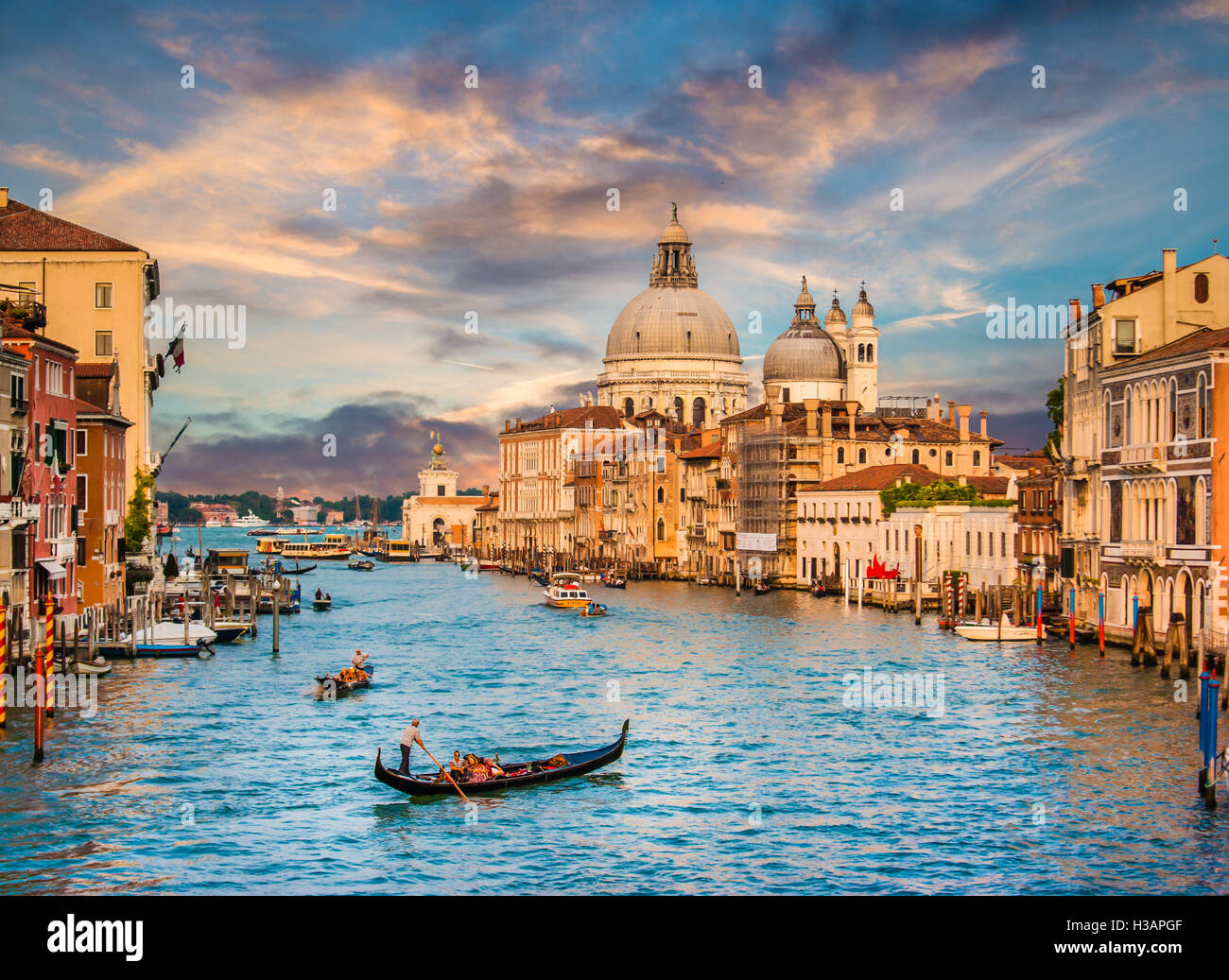 Classic view of traditional Gondola on famous Canal Grande with Basilica di Santa Maria della Salute at sunset in Venice, Italy Stock Photo