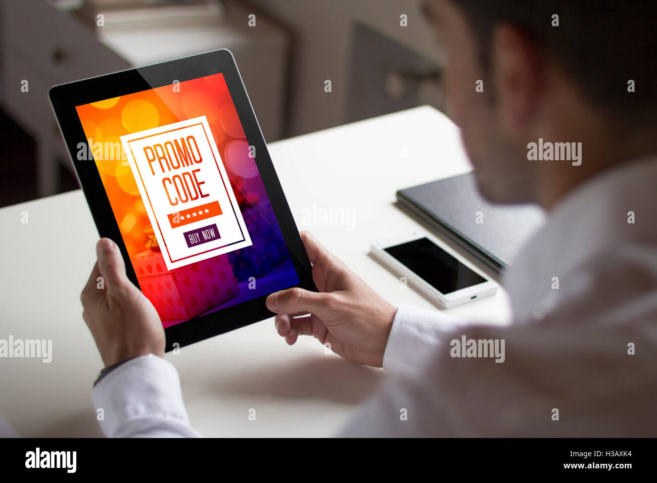 bussinessman at office holding a tablet exchanging a promotional code. All screen graphics are made up. Stock Photo