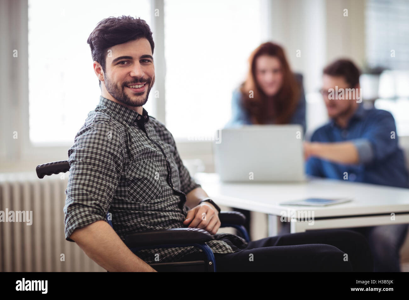 Businessman on wheelchair with coworkers Stock Photo