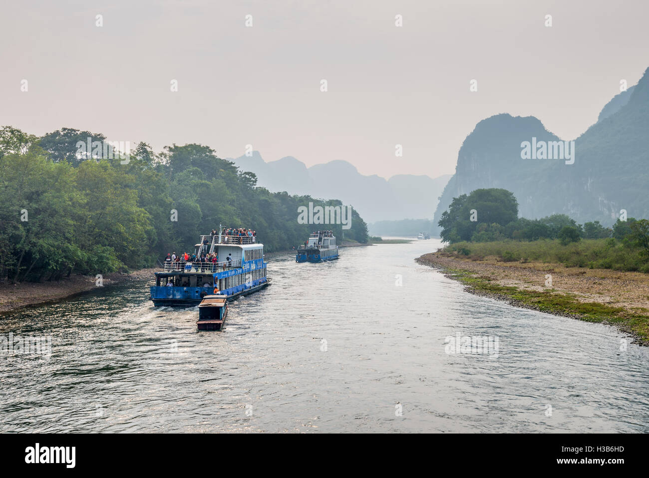 A tourist boats packed with tourists travels the magnificent scenic route along the Li river Stock Photo