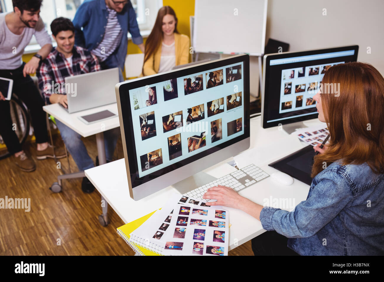 Editor Worker Computer Female photo editor working on computer against coworkers Stock Photo ...