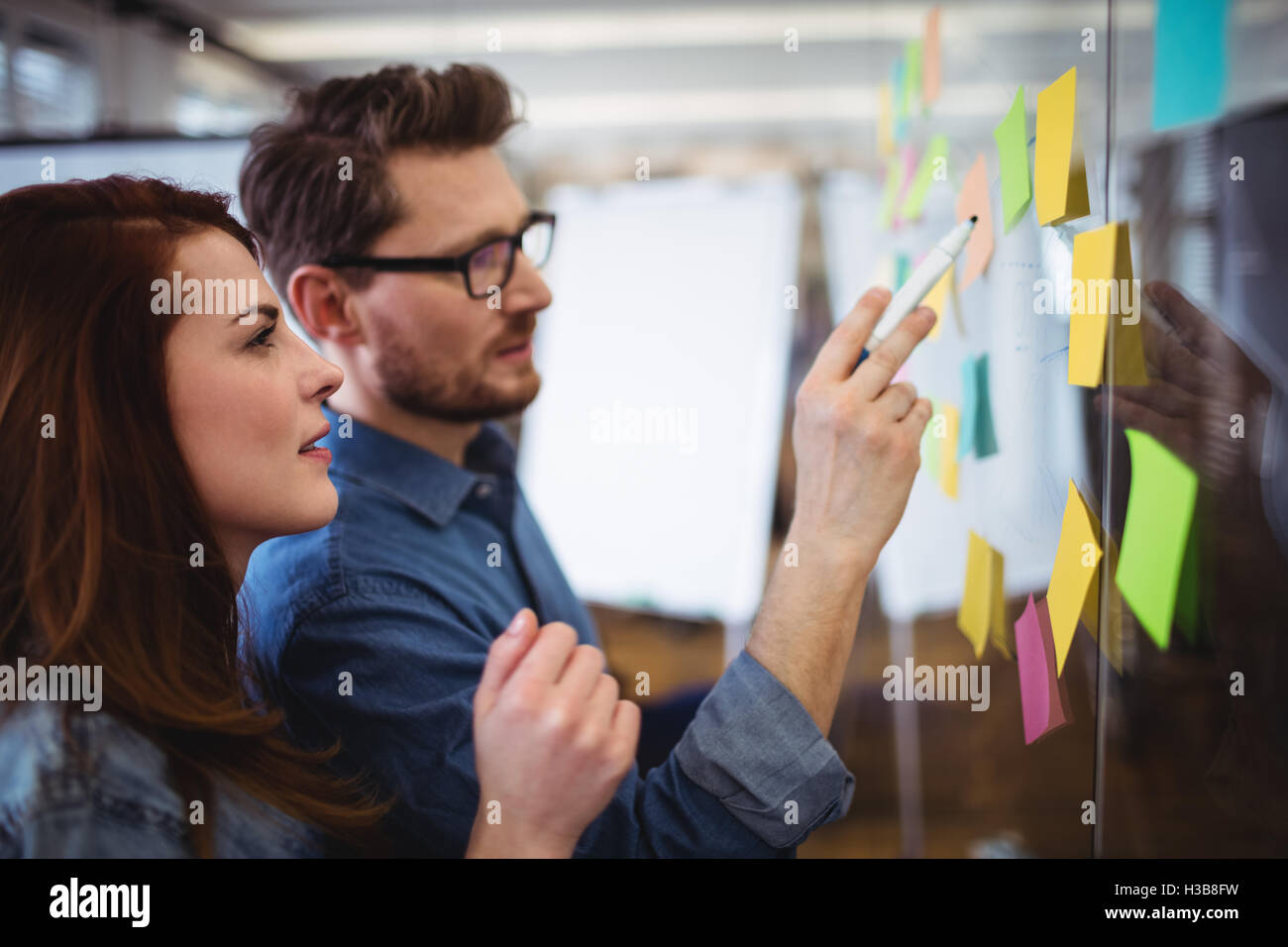 Creative business people looking at sticking notes Stock Photo - Alamy