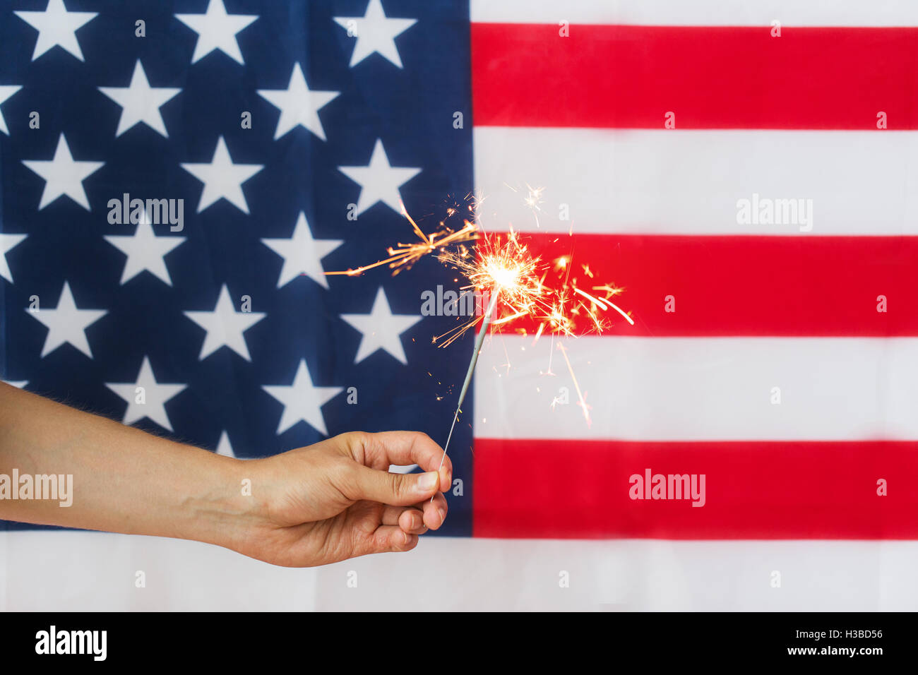 close up of hand with sparkler over american flag Stock Photo - Alamy