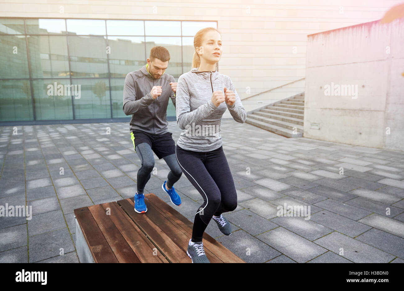 Two People Getting Steps In couple making step exercise on city street bench Stock Photo - Alamy