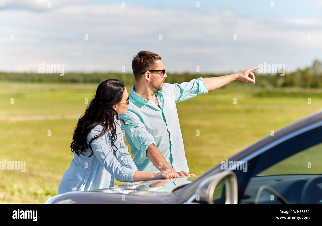 man and woman with car pointing finger outdoors Stock Photo