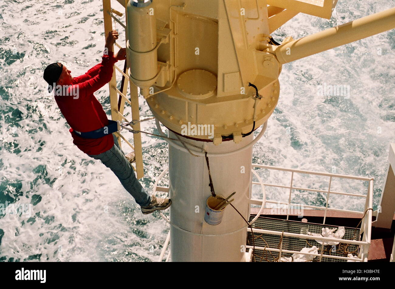 AJAXNETPHOTO. AT SEA. - PAINTING SHIP - A SAILOR ON AN OCEAN GOING CARGO SHIP PAINTING THE CRANE MAST HIGH ABOVE THE DECK.  PHOTO:JESSICA EASTLAND/AJAX  REF:40309 2 30003 Stock Photo