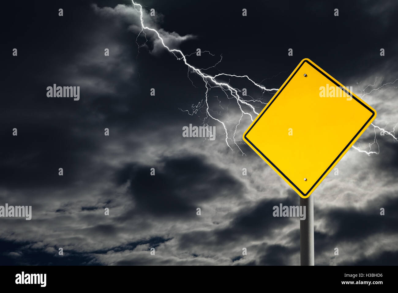 An empty traffic sign against a dark, cloudy and thunderous sky. Conceptually warning of danger ahead. Blank sign for copy space Stock Photo