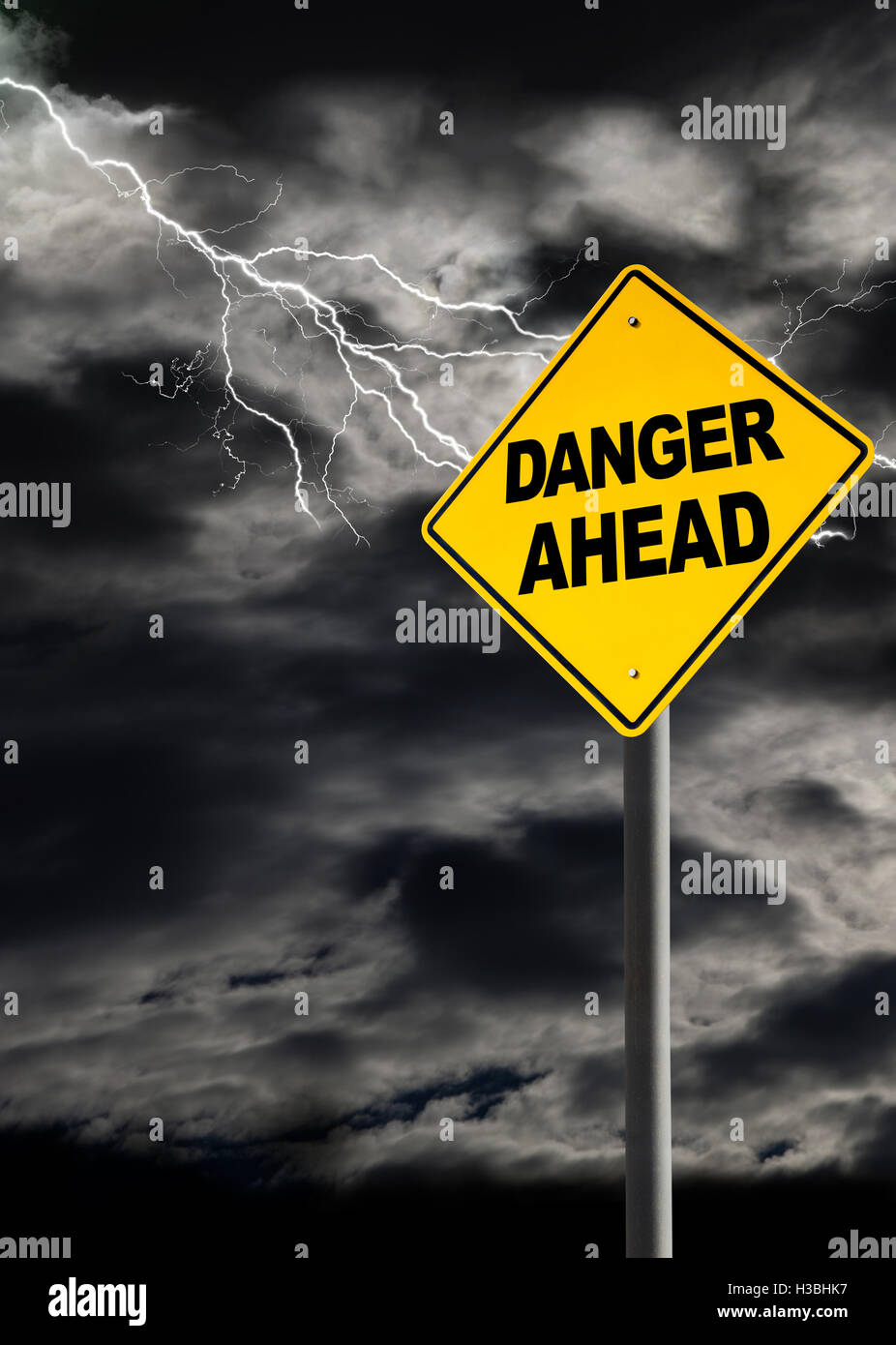 Danger Ahead sign against a dark, cloudy and thunderous sky. Conceptually warning of danger ahead. Blank sign for copy space and Stock Photo